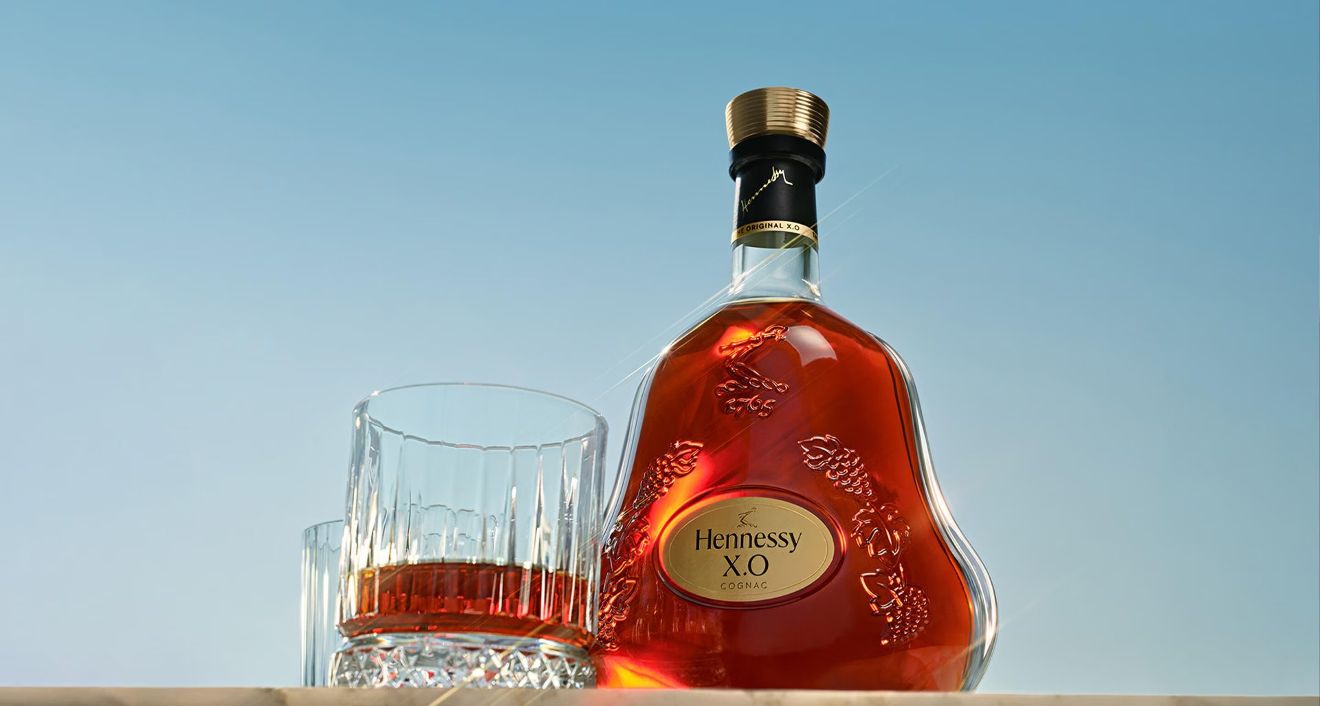 Hennessy X.O bottle and serve against a blue sky